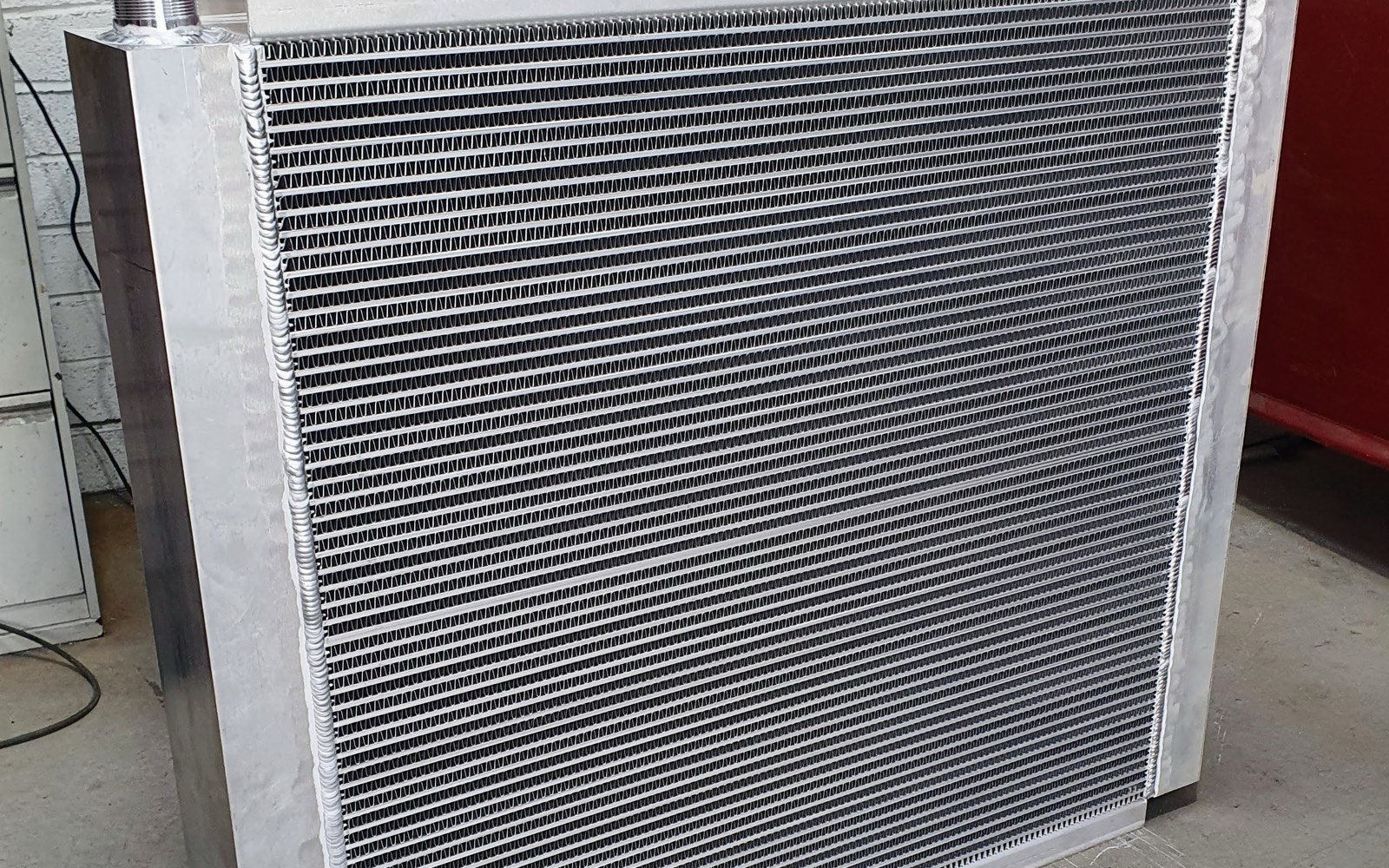 An aluminium radiator in the Kilcock Radiators workshop: hand-welded tanks, a threaded fitting and rows of fine louvred fins